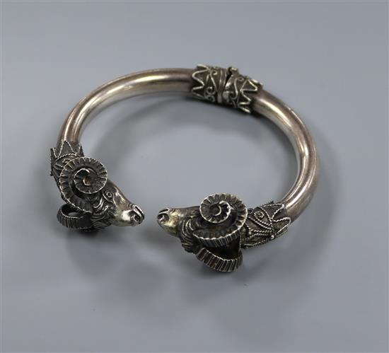 A white metal rams head torque bracelet.